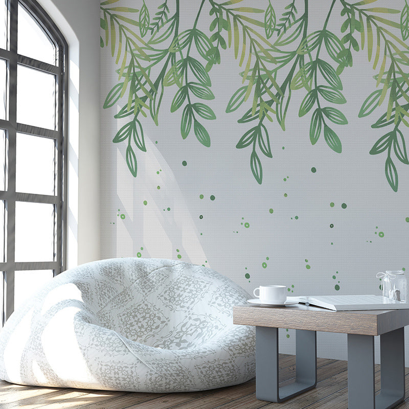 Wallpaper Kids Nursery Dubai A room with a wall decorated with green leaf patterns, featuring a beanbag chair and a small wooden table with a white mug and a book.
