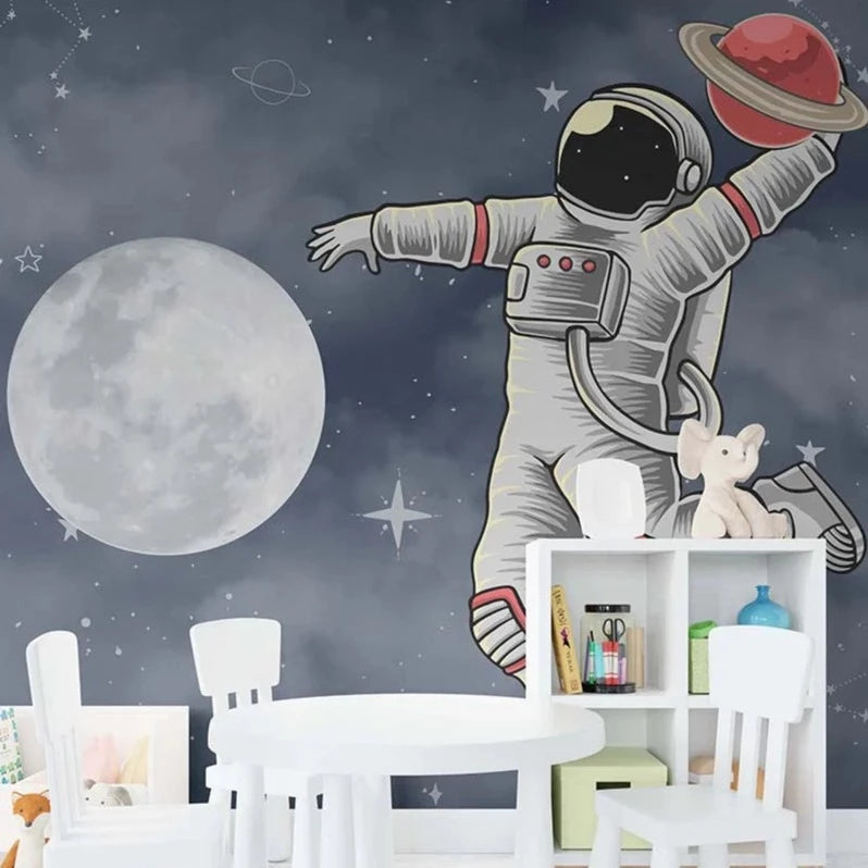 Wallpaper Kids Nursery Dubai Peps Wall A wall decal of an astronaut reaching out to a moon with a starry background, placed above a white shelf in a child's room.
