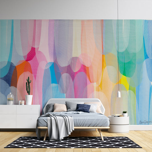 Wallpaper Kids Nursery Dubai Peps Wall A colorful abstract wall mural featuring shades of blue, pink, yellow, and orange applied generously across the wall, with a bed in the foreground and a small cactus on the bedside table.