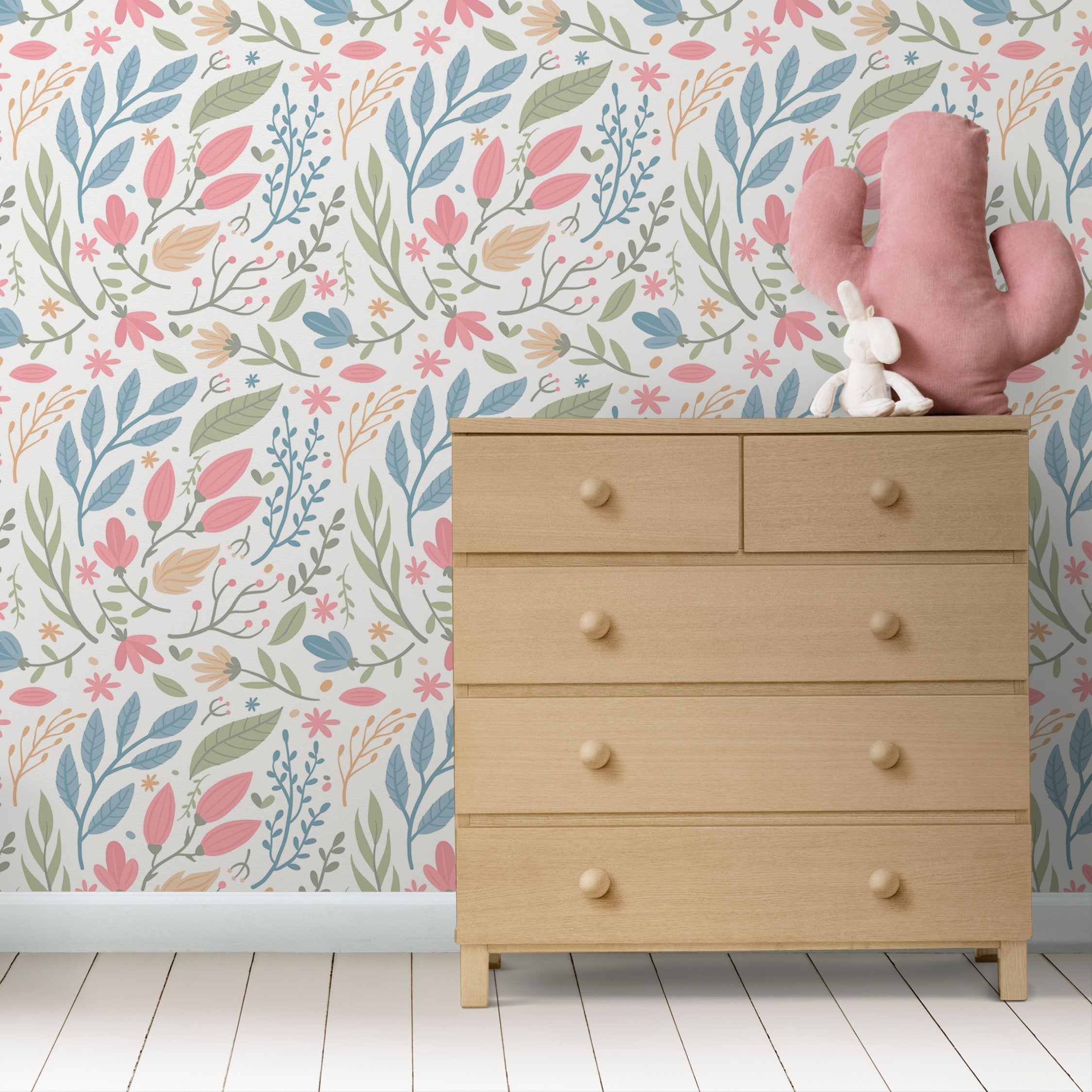 Wallpaper Kids Nursery Dubai Peps Wall A wall with a colorful floral and cactus pattern, featuring a wooden dresser with a pink toy on top.
