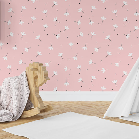 Wallpaper Kids Nursery Dubai Peps Wall A room with pink walls featuring a floral pattern, including a wooden stool and a white blanket, with a partial view of a white curtain.