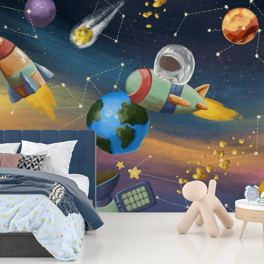Wallpaper Kids Nursery Dubai Peps Wall A colorful wall mural featuring space-themed elements such as rockets, planets, and an astronaut. The wall mural is applied to a wall in a room with a bed and a teddy bear on the floor.