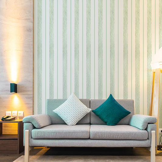 Wallpaper Kids Nursery Dubai Peps Wall A living room with green stripes on the wall, featuring a sofa with cushions, a side table with a lamp and a phone, and a wood floor.