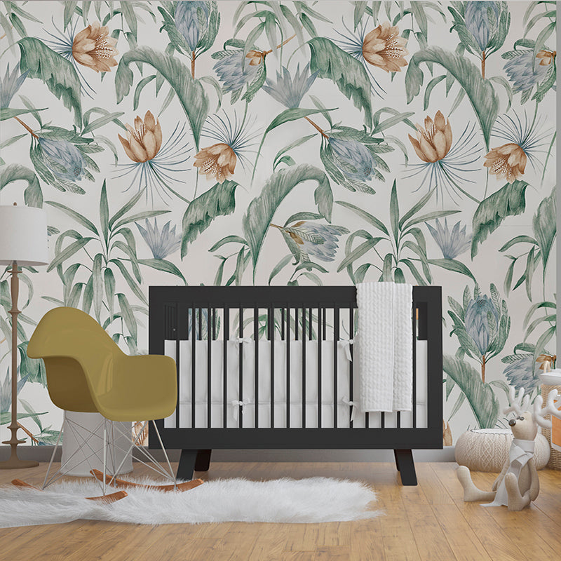 Wallpaper Kids Nursery Dubai Peps Wall A section of wallpaper with a floral leaf pattern in various shades of green, blue, and white, shown behind a black crib with a white bumper in a room with a yellow chair and a plush toy.
