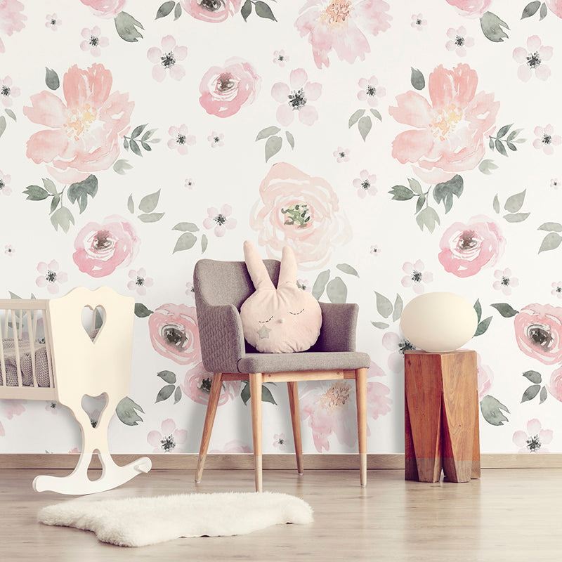 Wallpaper Kids Nursery Dubai Peps Wall A room with floral wallpaper featuring pink and white flowers and green leaves, a rocking chair, a grey chair, a wooden side table, a white sheep plush, and a decorative ball.