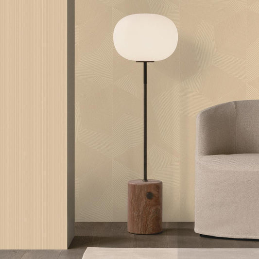 A modern floor lamp with a glowing white oval shade, a slim black stem, and a cylindrical wooden base, styled in a minimalist interior next to a light gray armchair.